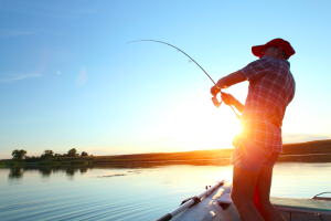 Jeune homme en train de pêcher sur un bateau.